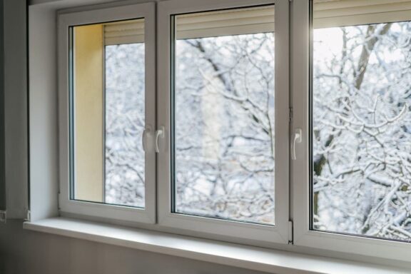 An interior view of modern vinyl windows looking out onto a snow-covered winter landscape, helping homeowners evaluate if energy-efficient argon gas windows are worth it.