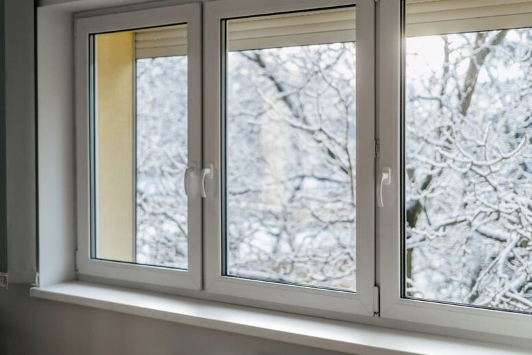 An interior view of modern vinyl windows looking out onto a snow-covered winter landscape, helping homeowners evaluate if energy-efficient argon gas windows are worth it.