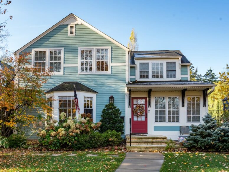A two-story home featuring light blue horizontal siding and a red front door, showcasing a classic combination of the most popular vinyl siding colors.